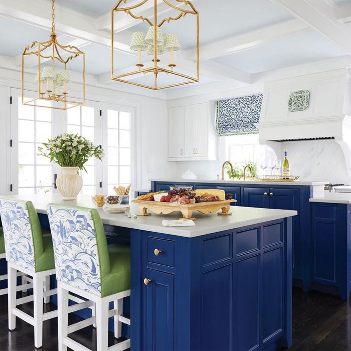 Dark blue kitchen cabinets with marble table countertop and green chairs