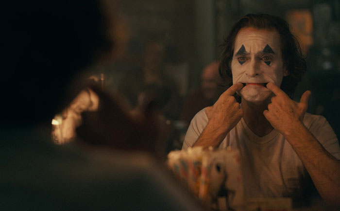 Joaquin Phoenix fake smiling with painted face 