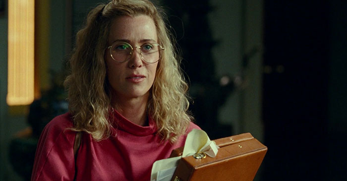 Kristen Wiig holding a suitcase and talking 