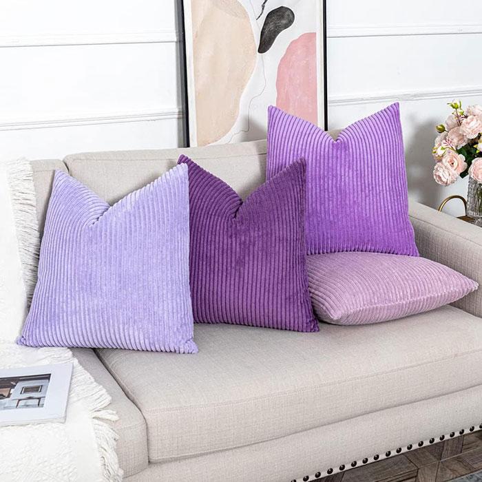 Different shades of violet colored pillows on sofa 