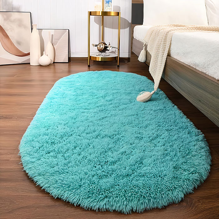 Turquoise colored rug near a white bed 