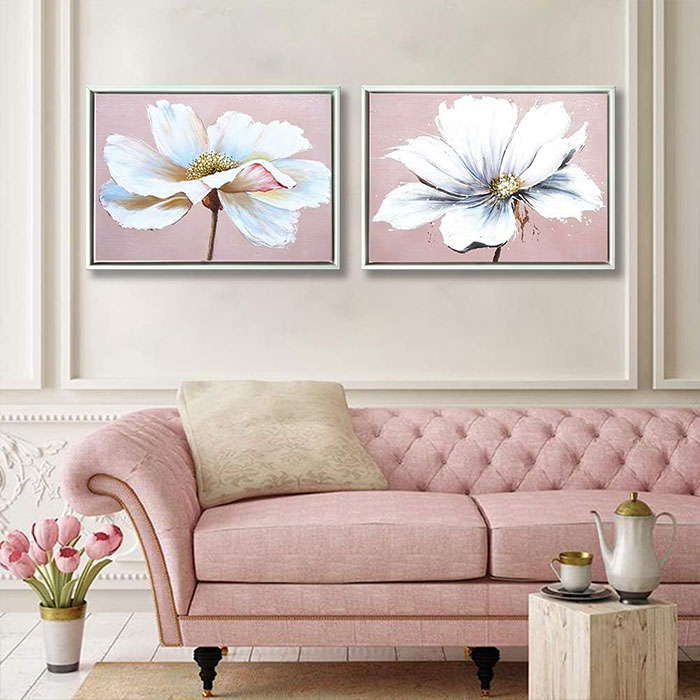 Pictures of flowers hanging above the pink couch.