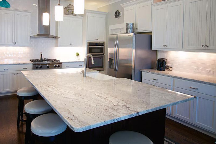 A beautiful kitchen with a white granite countertop kitchen island