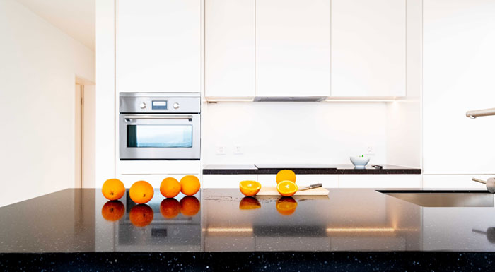 A shiny black granite countertop with oranges on it