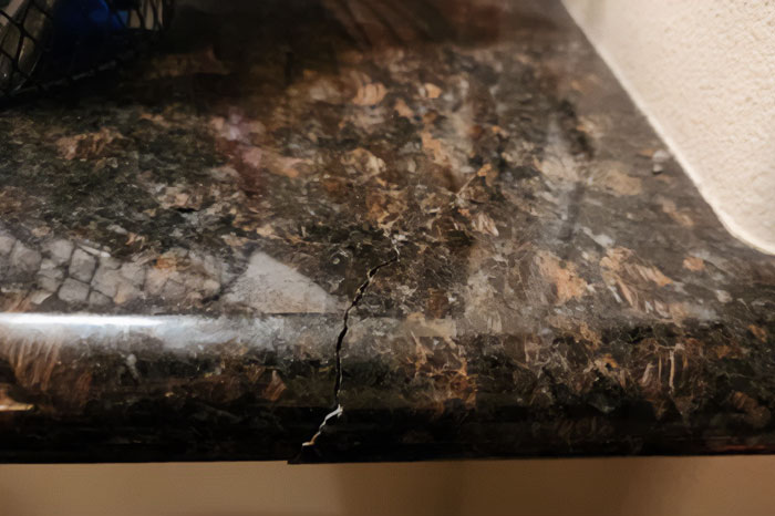 Close-up of a brown granite countertop that is cracked.