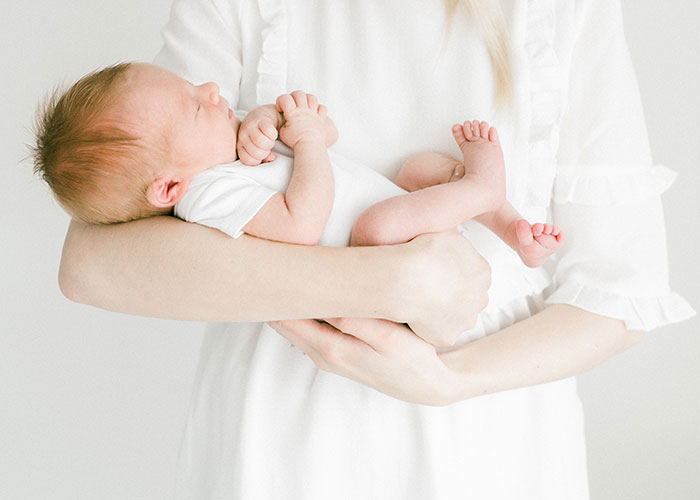Newborn baby with unique hair color held by mother, highlighting surprise and paternity test themes in family setting. Newborn baby with unique hair color held by mother, highlighting surprise and paternity test themes in family setting.