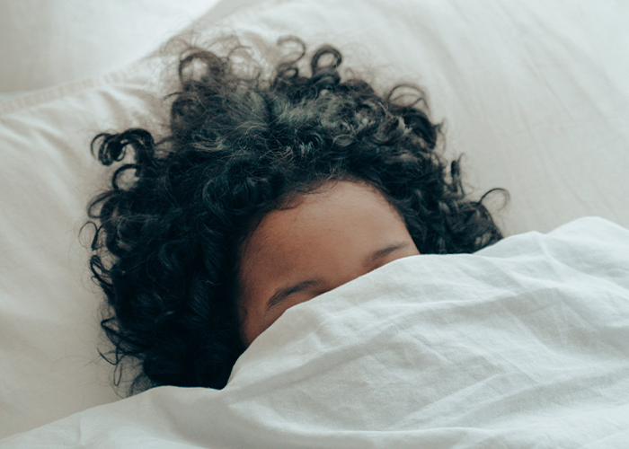 Baby with curly hair peeking from under white blanket, highlighting unique hair color in paternity test story. Baby with curly hair peeking from under white blanket, highlighting unique hair color in paternity test story.