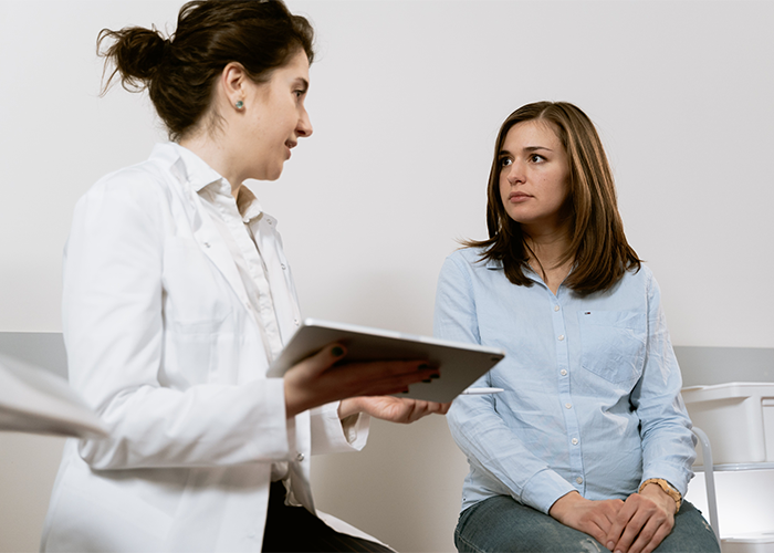 Woman anxiously listens to doctor holding tablet during paternity test discussion about baby’s hair color and results. Woman anxiously listens to doctor holding tablet during paternity test discussion about baby’s hair color and results.