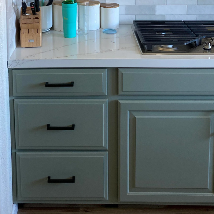 Green kitchen cabinets with black handles 