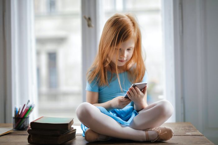 Girl sitting on the table and using a mobile phone 