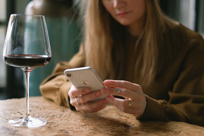 Woman using a mobile phone and drinking wine 
