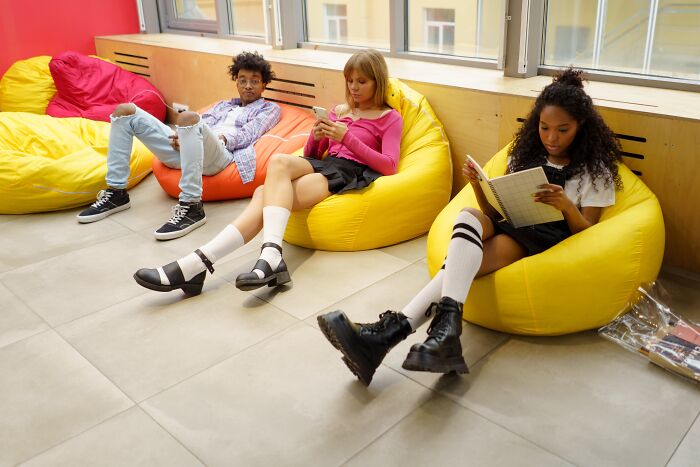 Three students sitting on yellow bean bags 