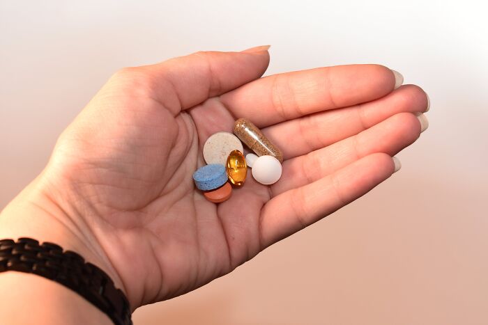 Woman holding multiple pill in her hand 