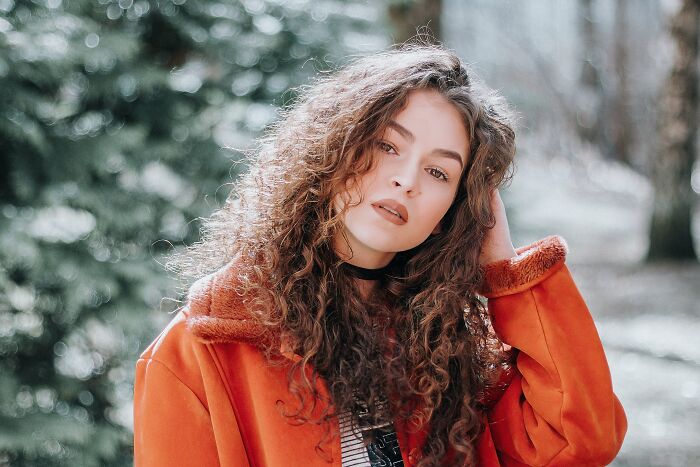 Woman in orange jacket with curly hair