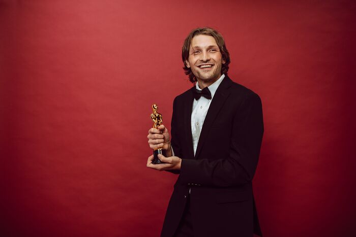 Man in a suit holding an award trophy 
