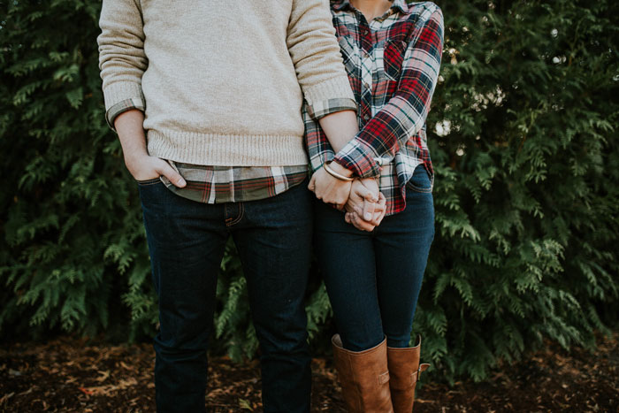 A couple holding hands in front of greenery, symbolizing family drama and relationship tension. A couple holding hands in front of greenery, symbolizing family drama and relationship tension.