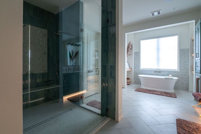Spacious Walk-in shower with a white tub near a window 