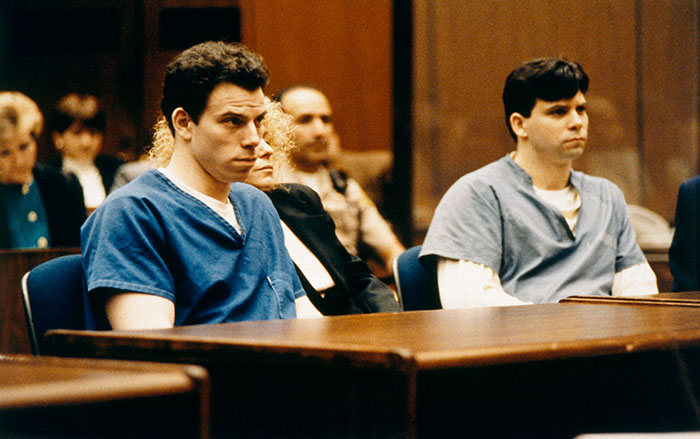 Two men in blue prison uniforms sitting in a courtroom, highlighting the Menendez Brothers' case. Two men in blue prison uniforms sitting in a courtroom, highlighting the Menendez Brothers' case.