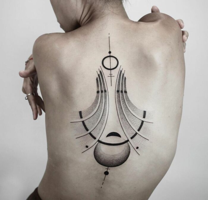 Abstract eclipse rays tattoo on woman’s back