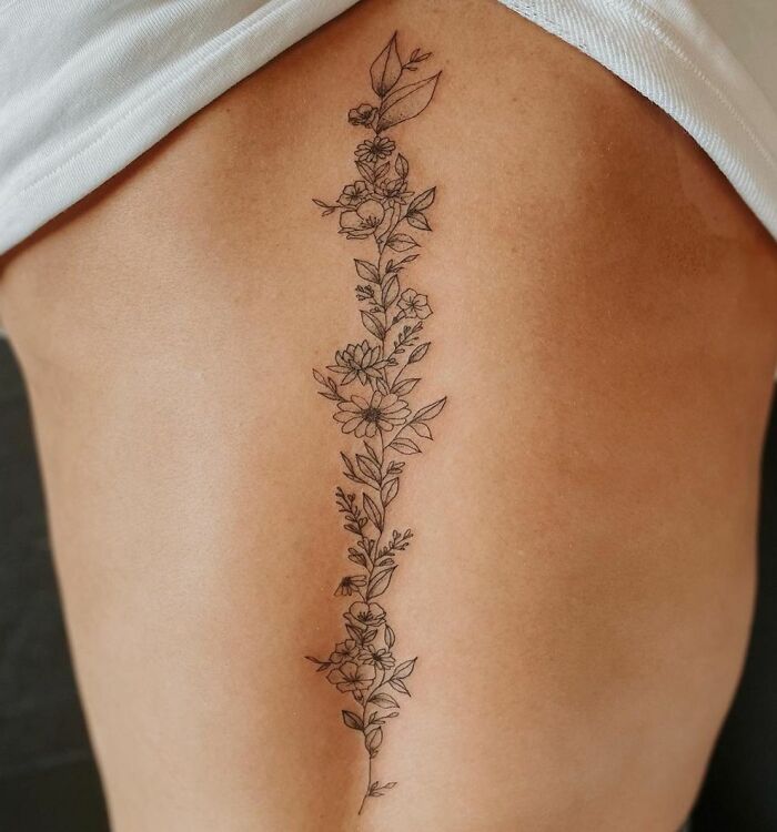 Black linear floral spine tattoo