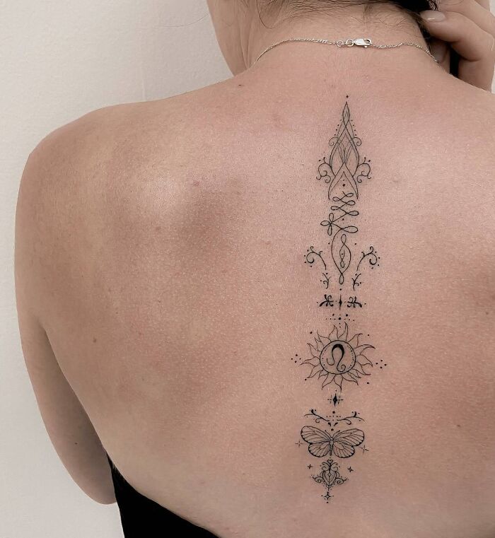 Delicate ornamental spine tattoo on woman’s back