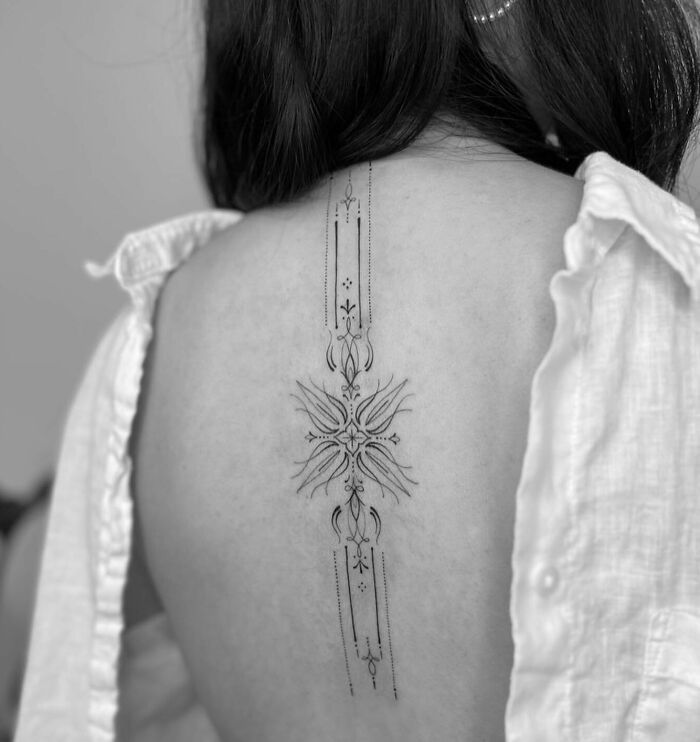Simple ornamental tattoo on woman’s back