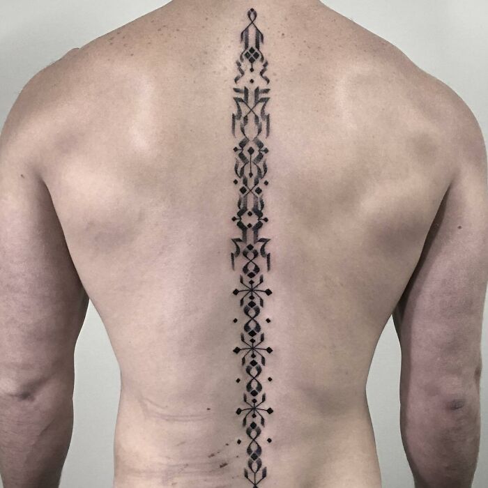 Black calligraphic spine tattoo