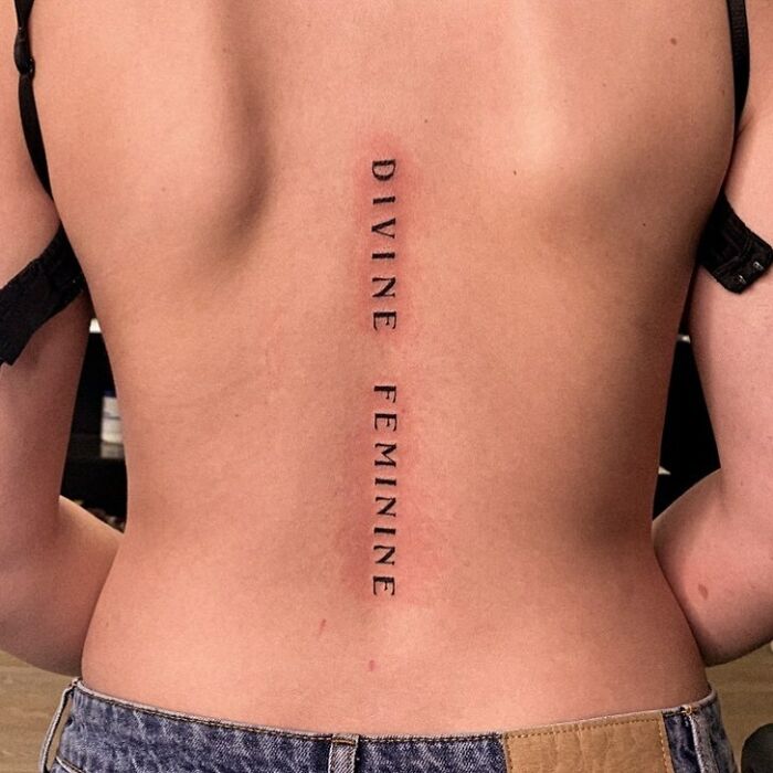 ‘DIVINE FEMINE’ lettering tattoo on back