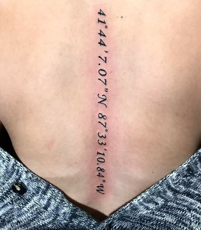 Black numbers tattoo on spine