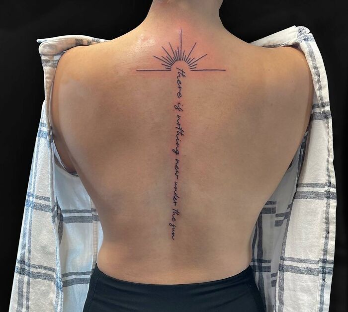 Sun and lettering tattoo on spine