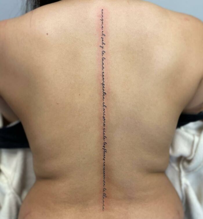 Script tattoo on woman’s spine