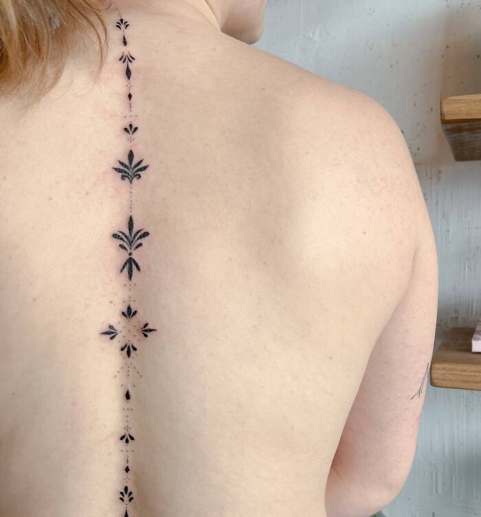 Black minimal ornamental spine tattoo