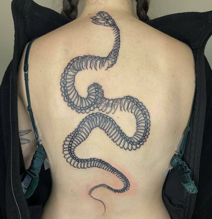 Large snake skeleton tattoo on woman’s back