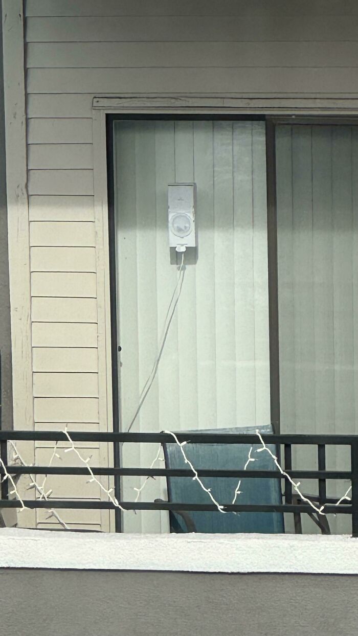 What Is This Thing On My Neighbors Balcony? About 1.5 Feet X 8 Inches. Some Type Of Electronic. Small White (Sometimes Red) Light Shining Occasionally. Looks Like It’s Suctioned To The Door