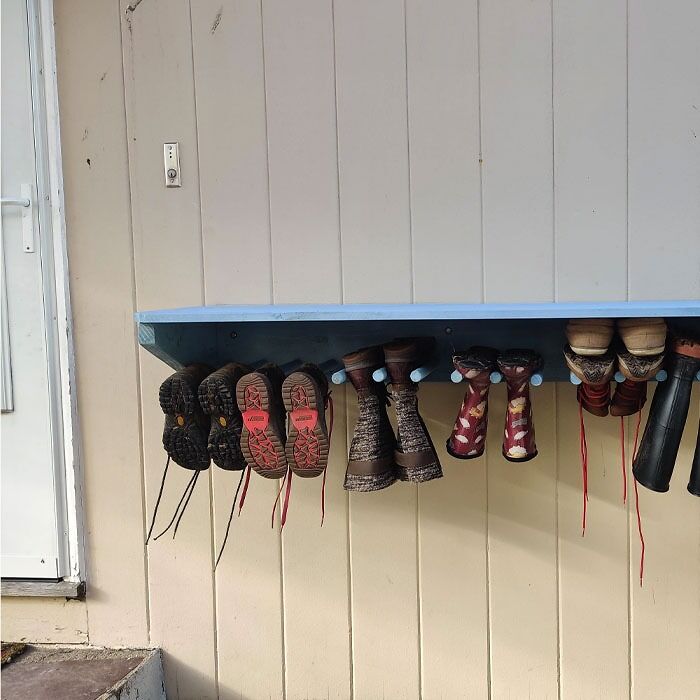 Shelve with hanging shoes near house doors