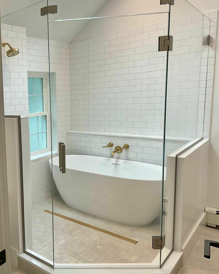 Bathtub in a walk-in shower with brass fixtures 