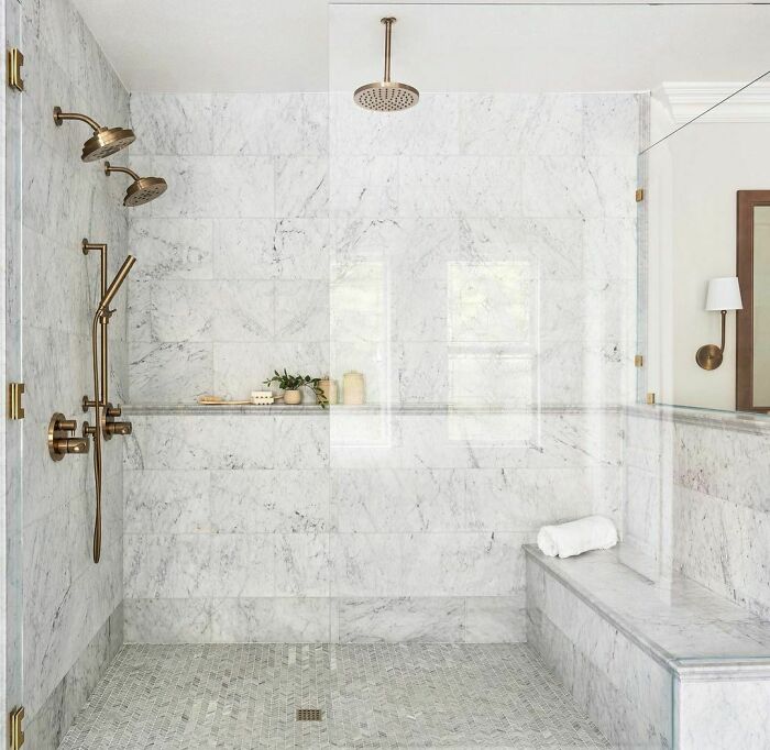 Bright and spacious walk-in shower with brass fixtures and rainfall showerhead 