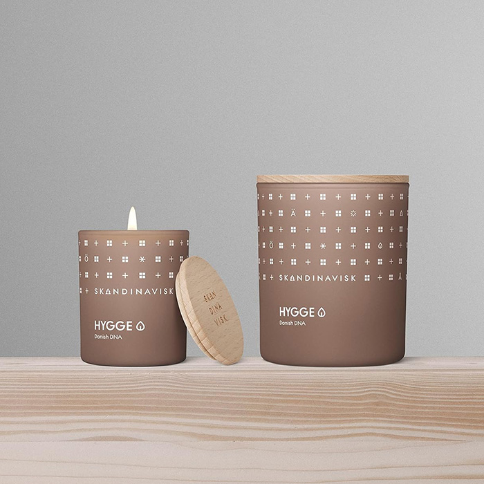 Two scented candles are on a wooden surface and one is lit Two scented candles are on a wooden surface and one is lit