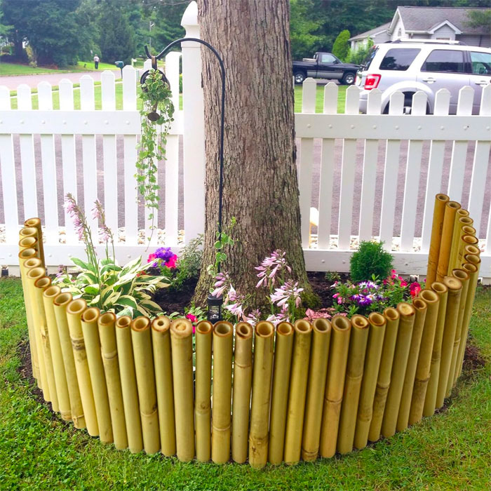 Picture of bamboo flower bed edging with colorful flowers near white fence