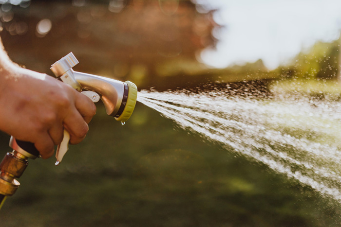 A person using a garden hose to spray water