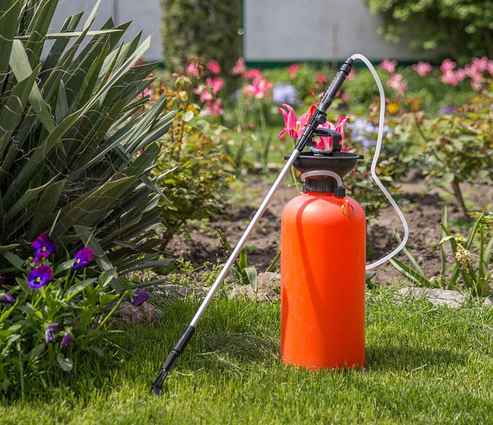 A large canister with a spray nozzle in a garden