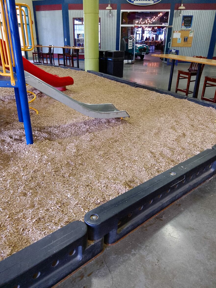 An Indoor Playground, With Wood Chips. Adjacent A Food Court