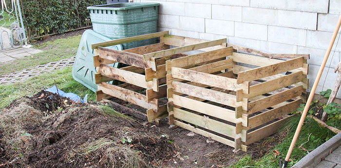 Two wooden boxes in a backyard ready to be filled with compost