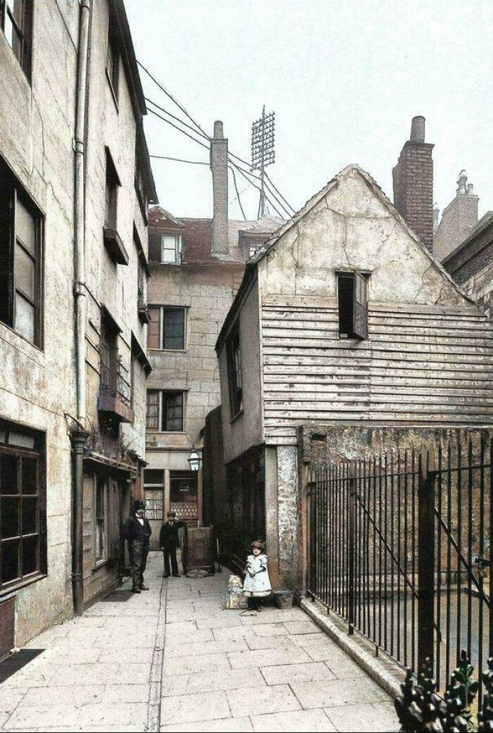 Cloth Fair, Smithfield, 1906, With What Appears To Be Weeds On Top Of A Ledge, On Close Inspection Looks Like Dead Plants In Pots. A Little Girl Plays With A Doll In A Box Pulled Along By String. Why An Opened Door So High Up?