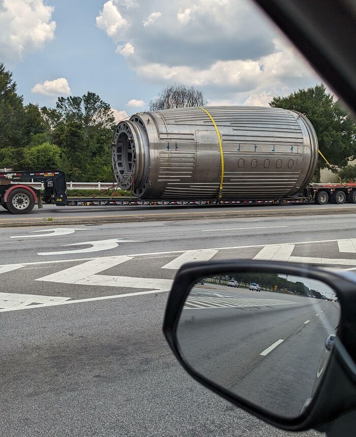 Large Metal Tube With Narrowed Front End, Transported With Police Escort, On An Extended Flatbed Trailer