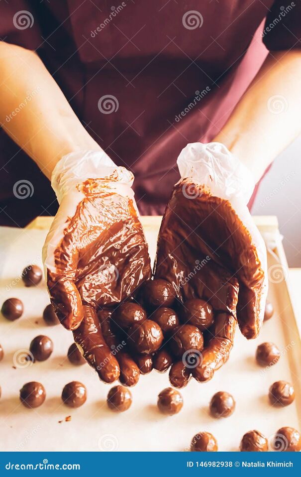 fabricaci-n-de-los-chocolates-hechos-mano-redondos-doused-con-el-chocolate-l-quido-en-las-manos-del-confitero-m-s-chocolatier-146982938.jpg