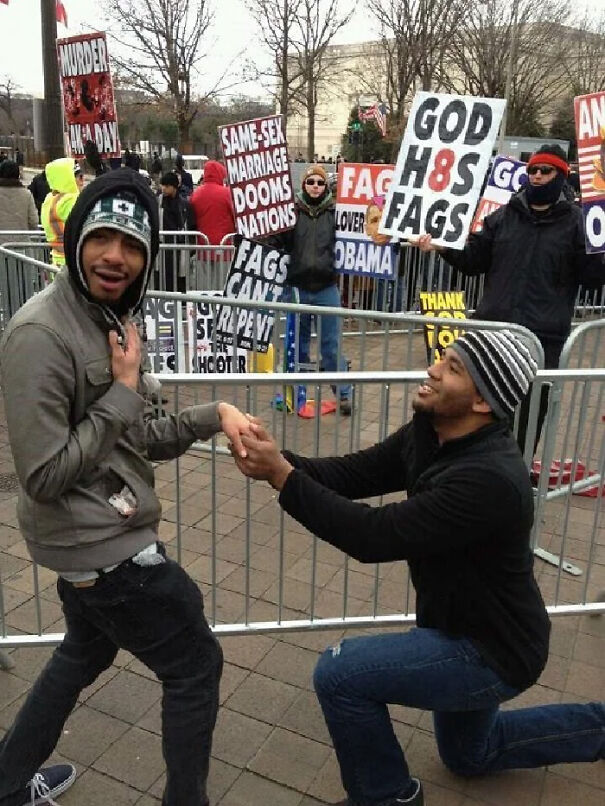 man proposing to another man in front of the protest agains gay couple 