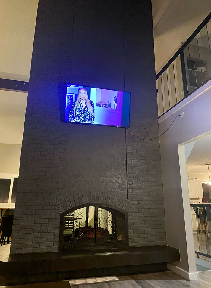 Airbnb House, TV Is Hung Halfway Up A Two-Story High Fireplace, Nearly Level With The Upper Floor