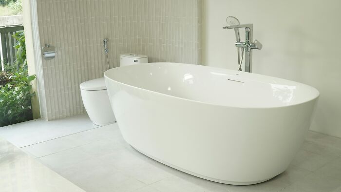 White ceramic bathtub near window