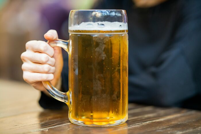 Person holding glass mug with beer